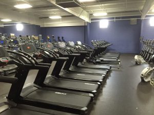 row of treadmills and bikes with fans on the ground